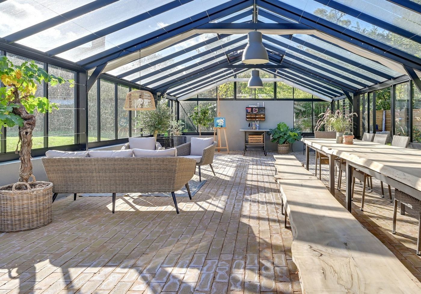 Inside a long, bright garden building with sofas and tables
